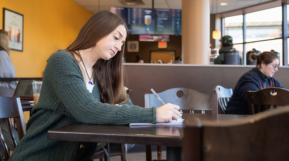 graduate student sitting at a table and writing