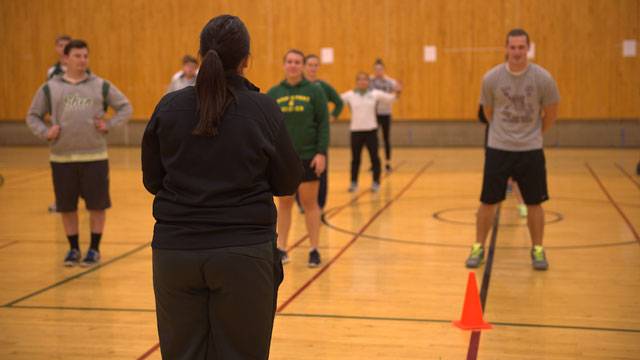 Gym teacher running through a workout with a class of students