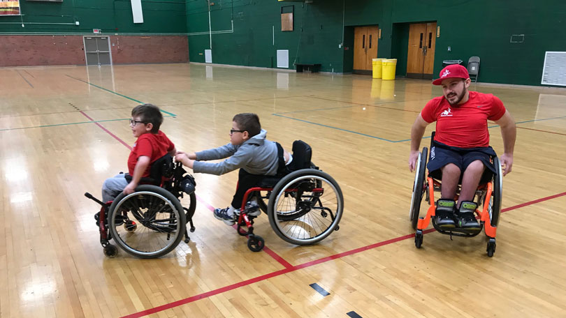 Children in wheelchairs pushing each other around in a gym