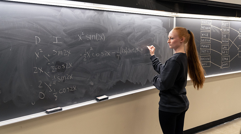 student writing equations on a chalkboard