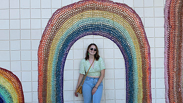 aimee albright posing next to a rainbow mural
