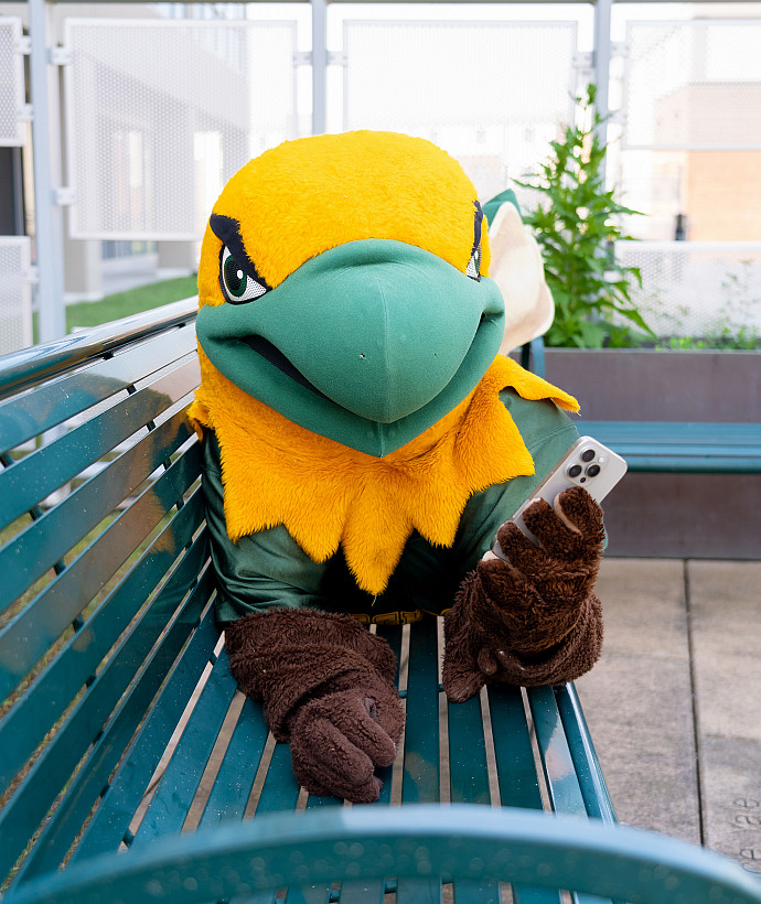 Ellsworth Eagle holding up a cellphone and laying on a bench.