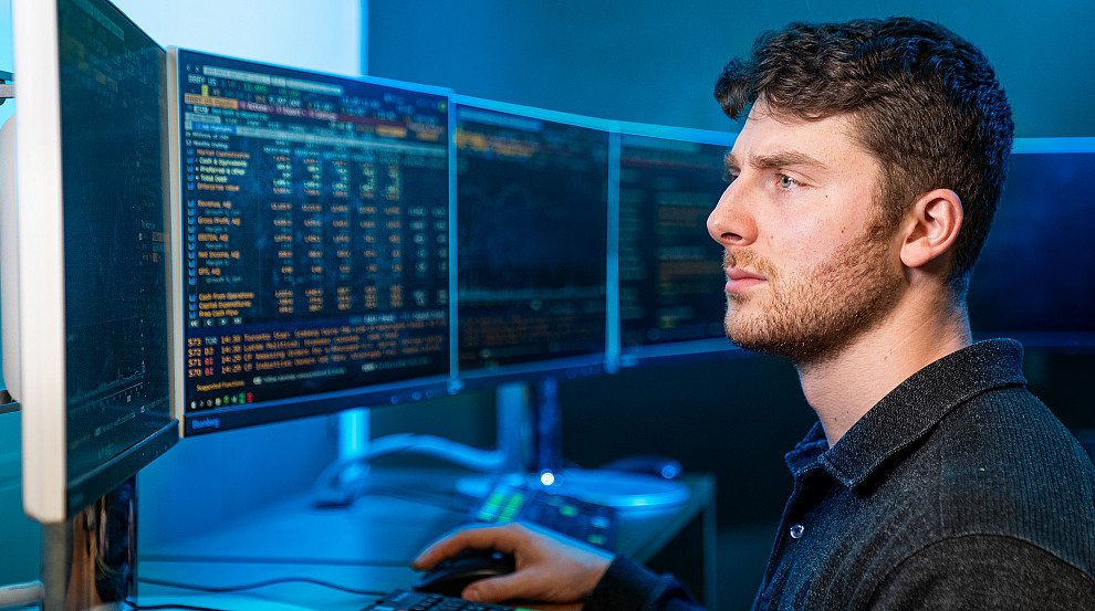 Student sitting and watching the real-time Bloomberg Terminals on campus