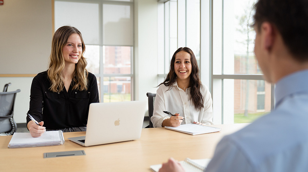 Three students talking in a conference room