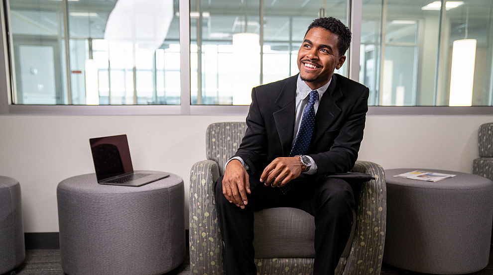 Student wearing a suit and tie sitting in a chair within the Academic Success Center