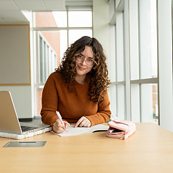 woman studying at laptop and writing notes