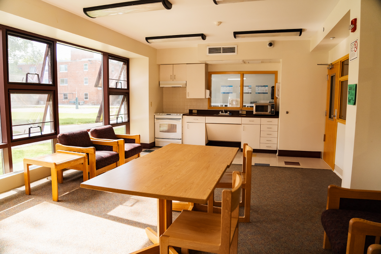 Wide view of corridor style lounge with a table, chairs, stove, sink, and microwave