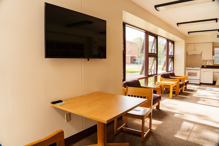 Close up of a wall-mounted TV and a table in a corridor style lounge
