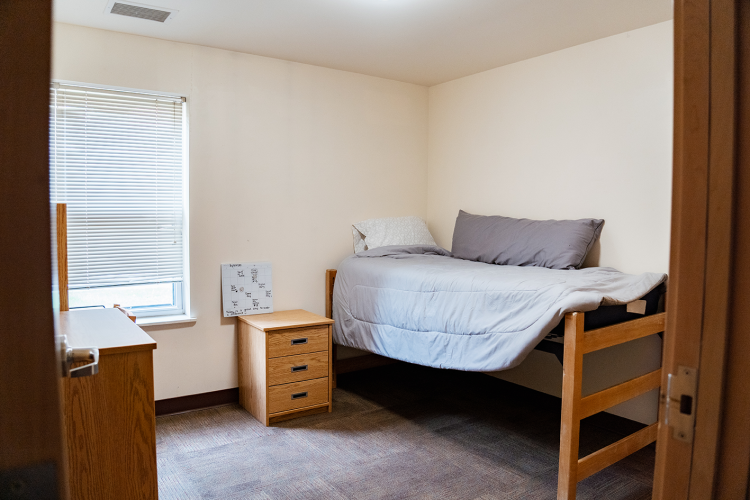 Entrance view of a bedroom with a nightstand and bed in a corner