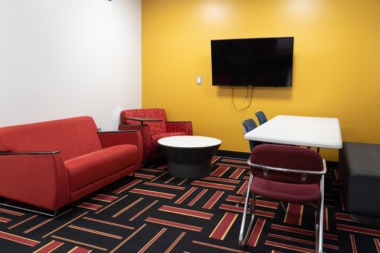Angled view of a lounge area with lounge chairs, chairs, table, and a wall-mounted TV