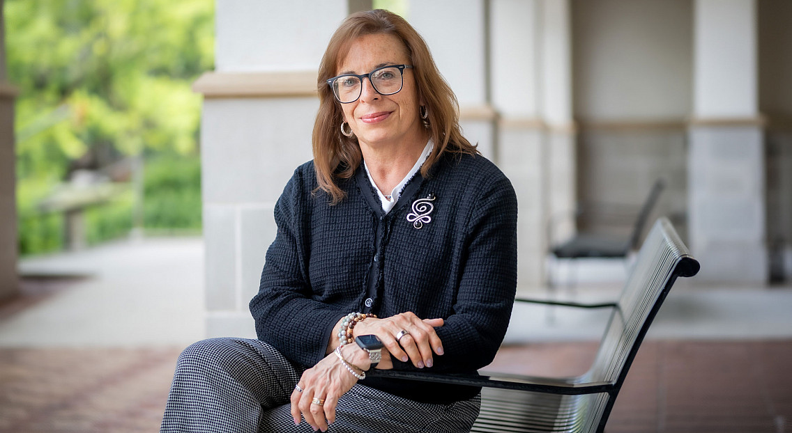woman in professional clothing posing outside on a chair for a headshot