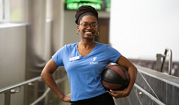 Anaheysha Baptiste-White holding a workout ball and wearing her YMCA uniform.