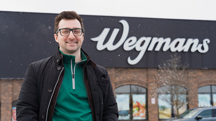 Brockport alum standing in front of Wegmans storefront.