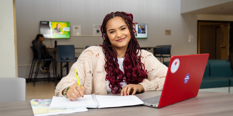 Zoe White sitting at a table with papers laying out and a pen in her hand.