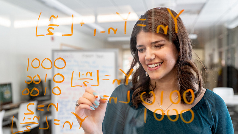 Alanna Pellicane writing equations on a clear board.