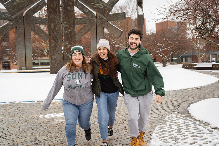 Three students walking together by the fountain in winter