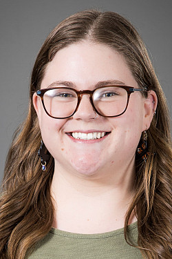 Catie Dietrich, a white woman with medium length light brown hair and square brown glasses.